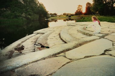 küçük kız bir miktar üzerinde park lake yakınındaki ördek besleme