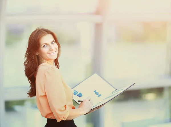 Attractive business woman holding a folder with charts and diagrams in office — Stock Photo, Image