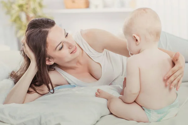 Portret van gelukkige moeder en jarige baby op het bed in de slaapkamer — Stockfoto