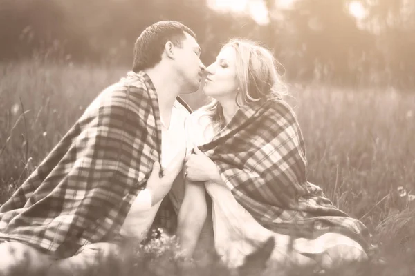 Glückliches Paar - schwangere Frau und ihr Mann im Park, bedeckt mit einer warmen Decke — Stockfoto