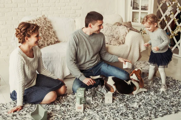 Familia feliz jugando con un perro mascota en la amplia sala de estar — Foto de Stock