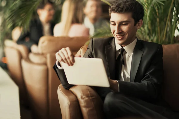 Ondernemer-beginner met een digitaal tablet zittend op de Bank in de lobby van een modern kantoor — Stockfoto