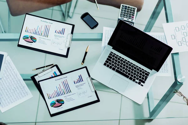 Mesa de trabajo de hombre de negocios con gráficos financieros, calculadora y un ordenador portátil —  Fotos de Stock