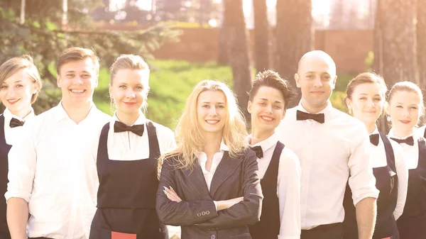 Eine große Gruppe freundlicher Kellner und Kellnerinnen, die hintereinander in einer Reihe stehen — Stockfoto