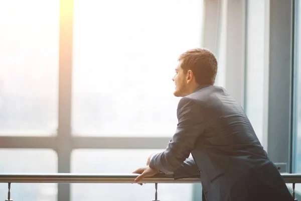 Retrato de una ventana de hombre de negocios guapo sonriente de fondo mirando al lado de un texto virtual — Foto de Stock