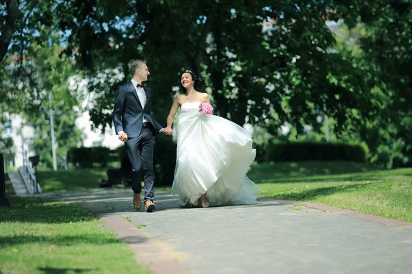 Νεόνυμφο ζευγάρι περπάτημα στο πάρκο την ημέρα του γάμου. — Φωτογραφία Αρχείου
