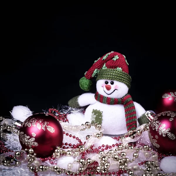Весела іграшка сніговик і різдвяні прикраси на чорному тлі — стокове фото