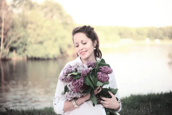 Portrait de jeune femme enceinte avec un bouquet de lilas sur une ba — Photo