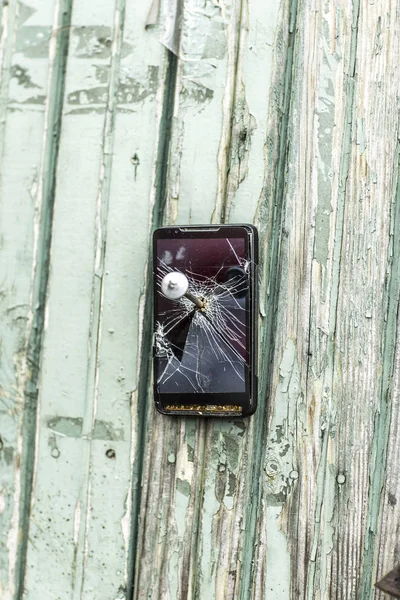 Conceito de tecnologia obsoleta: telefone celular pregado na cerca de um prego grande — Fotografia de Stock