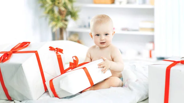 Um ano de idade bonito bebê brincando com compras em caixas no sofá — Fotografia de Stock