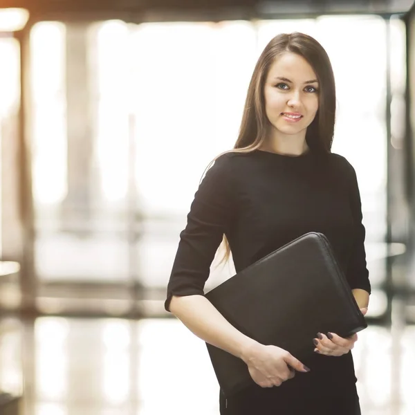 Retrato de jovem mulher de negócios bonito sorrindo no escritório, as mãos da pasta — Fotografia de Stock