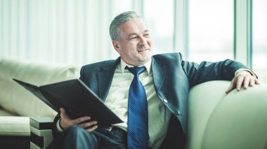 başarılı bir iş adamı özel ofisinde kanepede oturan yeni bir sözleşme dikkate alınarak