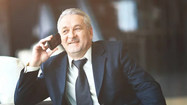 Hombre de negocios sonriente sentado y hablando por teléfono — Foto de Stock