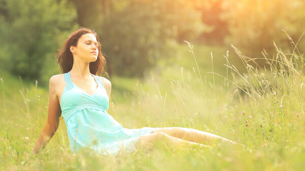 Красивая молодая женщина наслаждается солнцем на летнем поле
