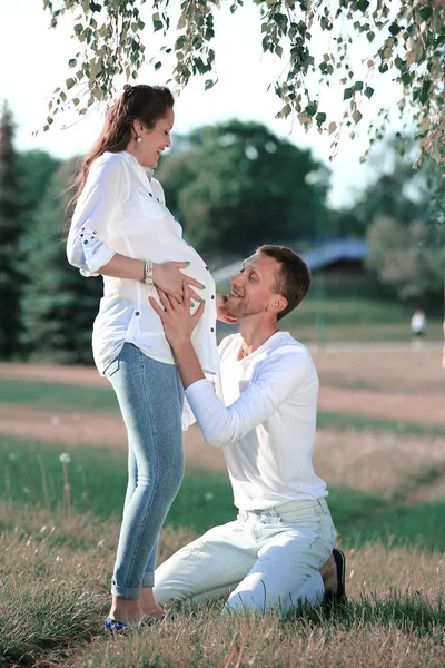 Šťastný manžel objímá svou těhotnou manželku na procházce v parku — Stock fotografie
