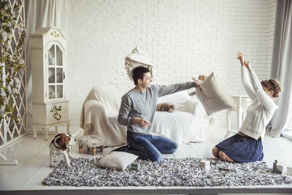 Feliz pareja en broma sostiene la pelea de almohadas en el sofá en la sala de estar — Foto de Stock