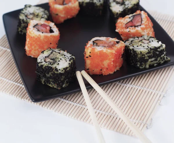 Different types of Maki sushi on a black plate — Stock Photo, Image