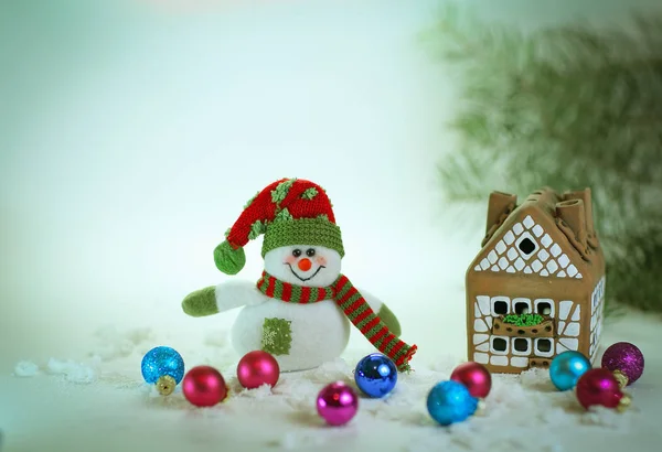 Speelgoed sneeuwpop en een peperkoek huis op een lichte achtergrond. — Stockfoto