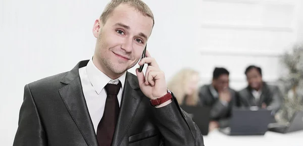 На переднем плане молодой бизнесмен разговаривает по мобильному телефону — стоковое фото