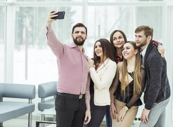 Equipo profesional de negocios haciendo selfie mientras está de pie cerca de la ventana en la oficina — Foto de Stock