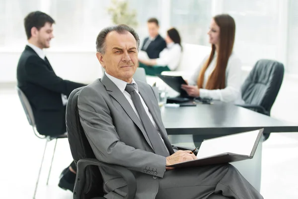 Hombre de negocios senior con un portapapeles en el fondo de la oficina — Foto de Stock