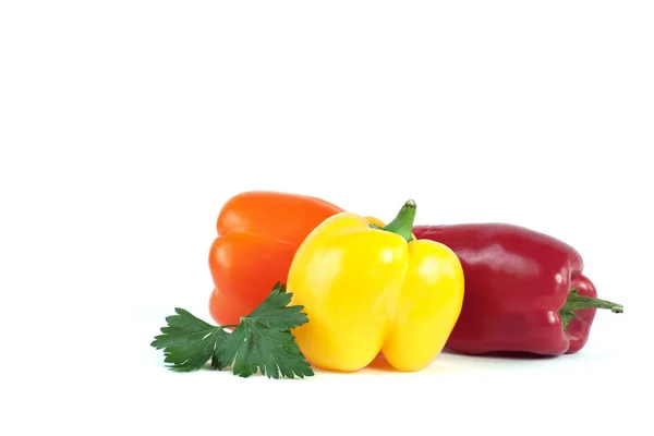 Three sweet peppers and a sprig of parsley isolated on white — Stock Photo, Image