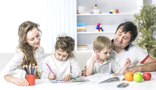 Mamá y papá están pintando con los niños sentados a la mesa en la guardería —  Fotos de Stock