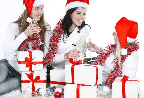 Noel hediyeleri ve bardak şampanya ile Santa Claus şapka üç genç kadın — Stok fotoğraf