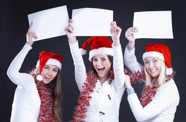 Três meninas no traje de Papai Noel mostrando folha em branco — Fotografia de Stock