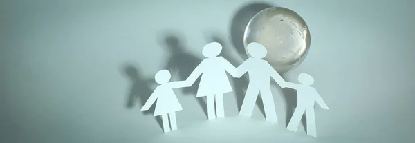 Счастливая семья бумажных людей, стоящих у стеклянного глобуса — стоковое фото