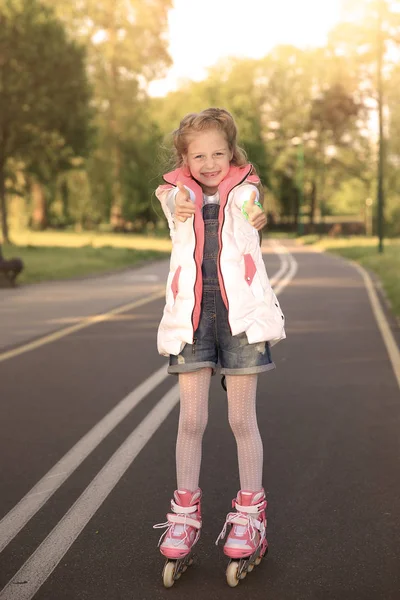 Gadis kecil yang bahagia di roller skates membuat gerakan jempol di t — Stok Foto