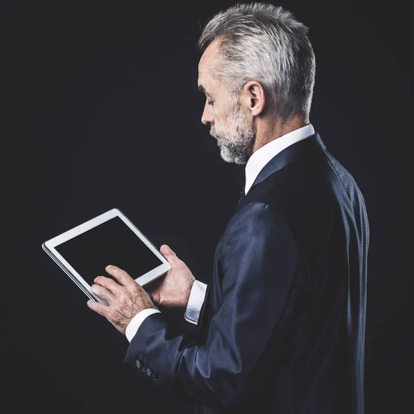 Erfaren affärsman med digital tablett på svart bakgrund. — Stockfoto