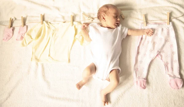 Recién nacido y ropa de bebé en un primako de madera en una luz b —  Fotos de Stock