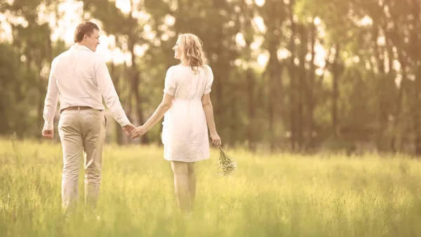 Happy couple - pregnant woman and her husband go on a picnic  the grass. — Stock Photo, Image