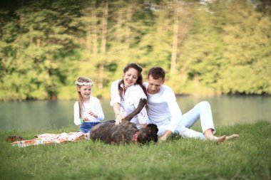 Güneşli bir yaz gününde piknikte köpekli mutlu bir aile. pregn