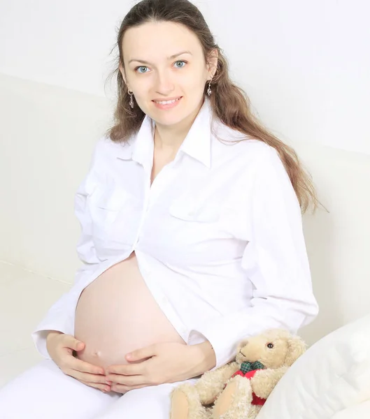 Jonge mooie zwangere vrouw op de Bank. — Stockfoto