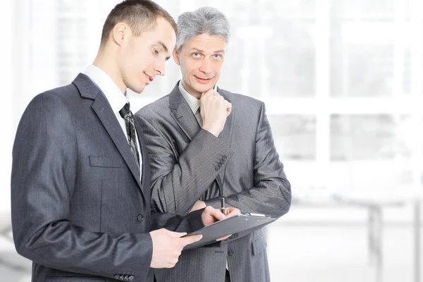 Zwei Geschäftsleute im Gespräch, indem sie wichtige Dokumente studieren — Stockfoto