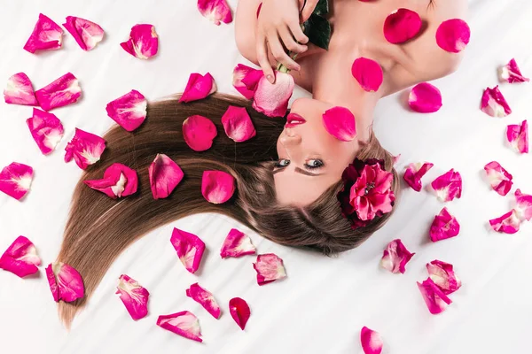 Schönes modisches Mädchen, das zwischen Rosenblättern liegt — Stockfoto