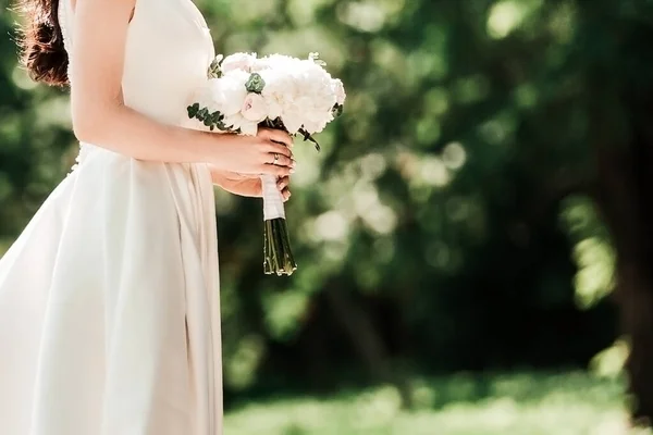 Belle jeune femme en robe de mariée debout dans le parc . — Photo