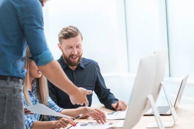 İş adamları çalışma belgelerini hafif bir ofiste tartışıyor..