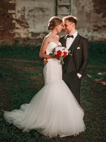 Bride with a wedding bouquet and the groom standing near the old manor — ストック写真