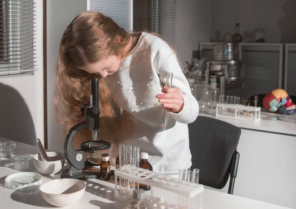 Teenage girl uses a microscope in a school laboratory. — ストック写真