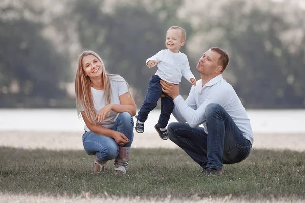 Eltern und ihr kleiner Sohn spielen mit dem Ball auf dem Rasen. — Stockfoto