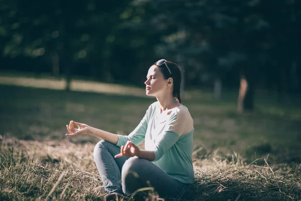 Hermosa joven meditando en posición de loto sentado en el césped. — Foto de Stock