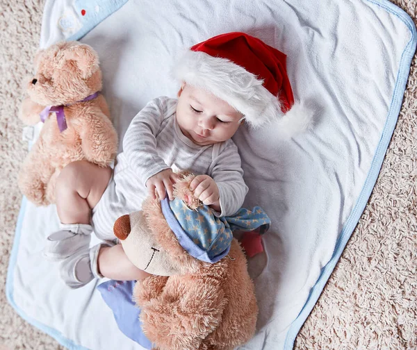 Szczęśliwe dziecko w czapce Mikołaja z miękkimi zabawkami — Zdjęcie stockowe