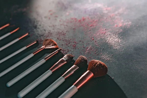 nine professional makeup brushes on a black background