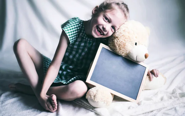 Niña sosteniendo un juguete suave con palabras de felicitación para el —  Fotos de Stock