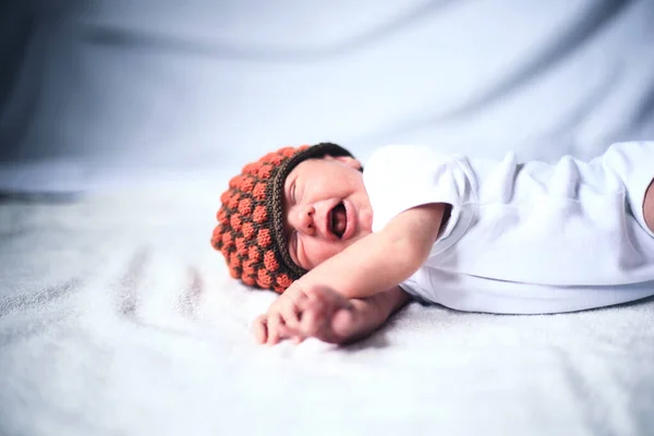 Pasgeboren baby in gebreide muts liggend op het witte doek. — Stockfoto