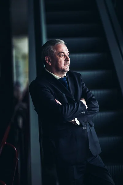 Erfolgreicher Geschäftsmann auf der Treppe eines modernen Büros vor dunklem Hintergrund — Stockfoto