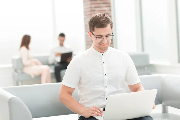 De près. homme d'affaires utilisant son ordinateur portable tout en étant assis sur le canapé de bureau  . — Photo